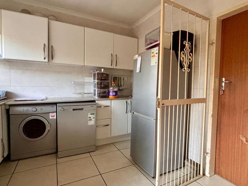 Functional laundry area featuring built-in cabinetry, tiled flooring, and a security gate, providing a practical space for household utility tasks.