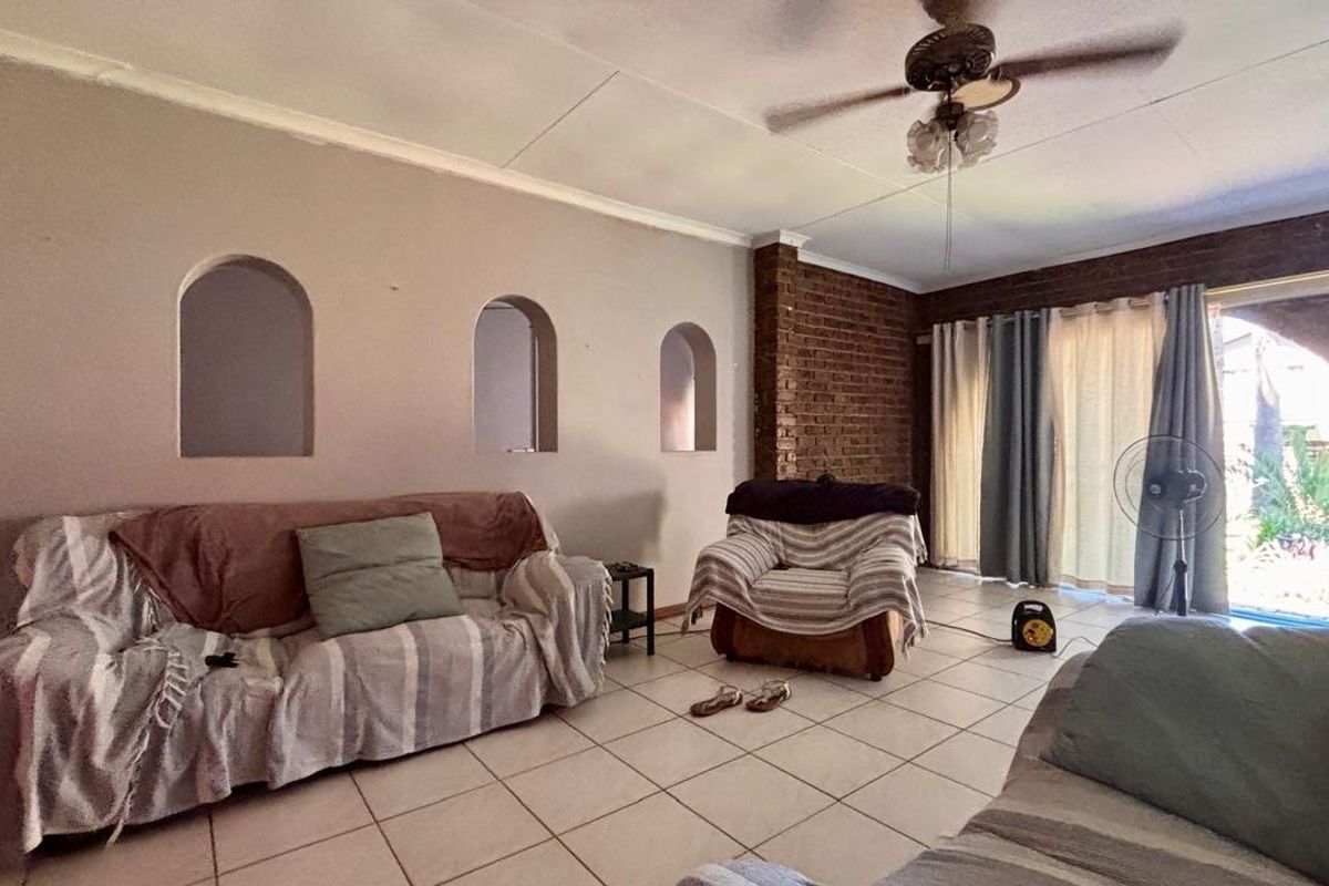 Living room featuring tiled flooring, exposed brick accents, and built-in wall niches, with direct access to the outdoor area through sliding glass doors.