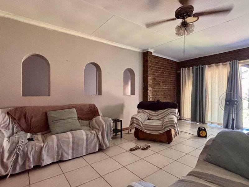 Living room featuring tiled flooring, exposed brick accents, and built-in wall niches, with direct access to the outdoor area through sliding glass doors.