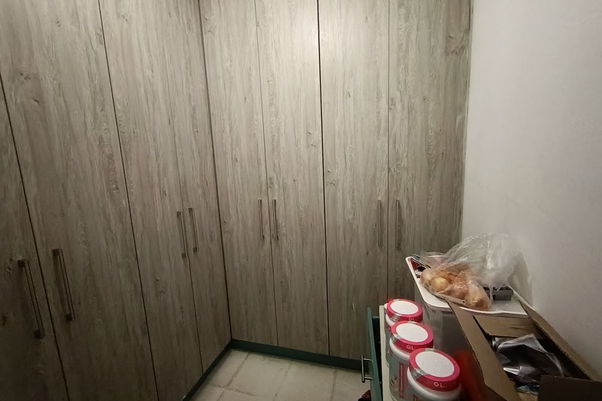 A functional walk-in closet or storage area featuring extensive floor-to-ceiling built-in cabinetry with a wood-grain finish.