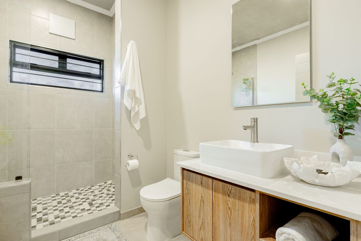 Modern bathroom featuring a walk-in shower with tiled flooring, a contemporary vessel sink vanity, and a wall-mounted mirror.