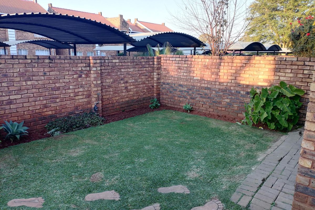A private rear garden featuring a brick boundary wall, a small lawn area, and decorative stone stepping stones.