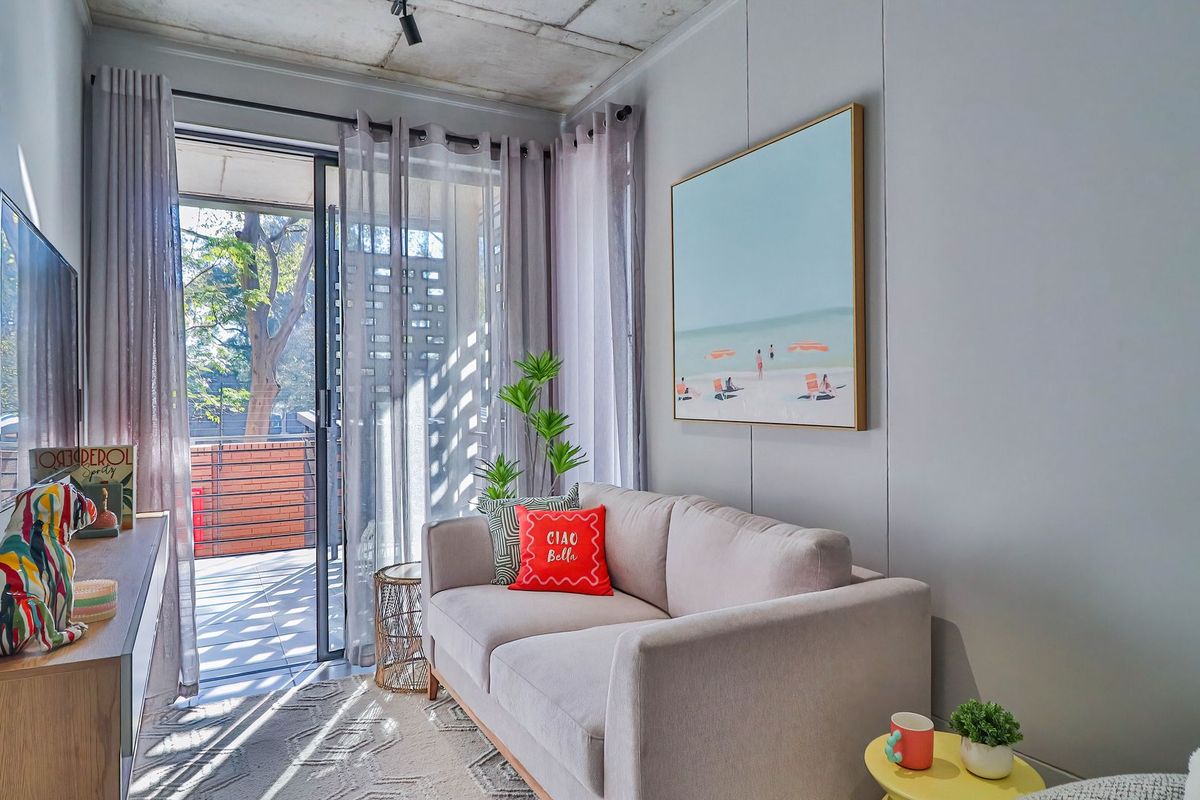 Modern living room featuring an exposed concrete ceiling, sleek panelled walls, and large sliding glass doors opening onto a private balcony.