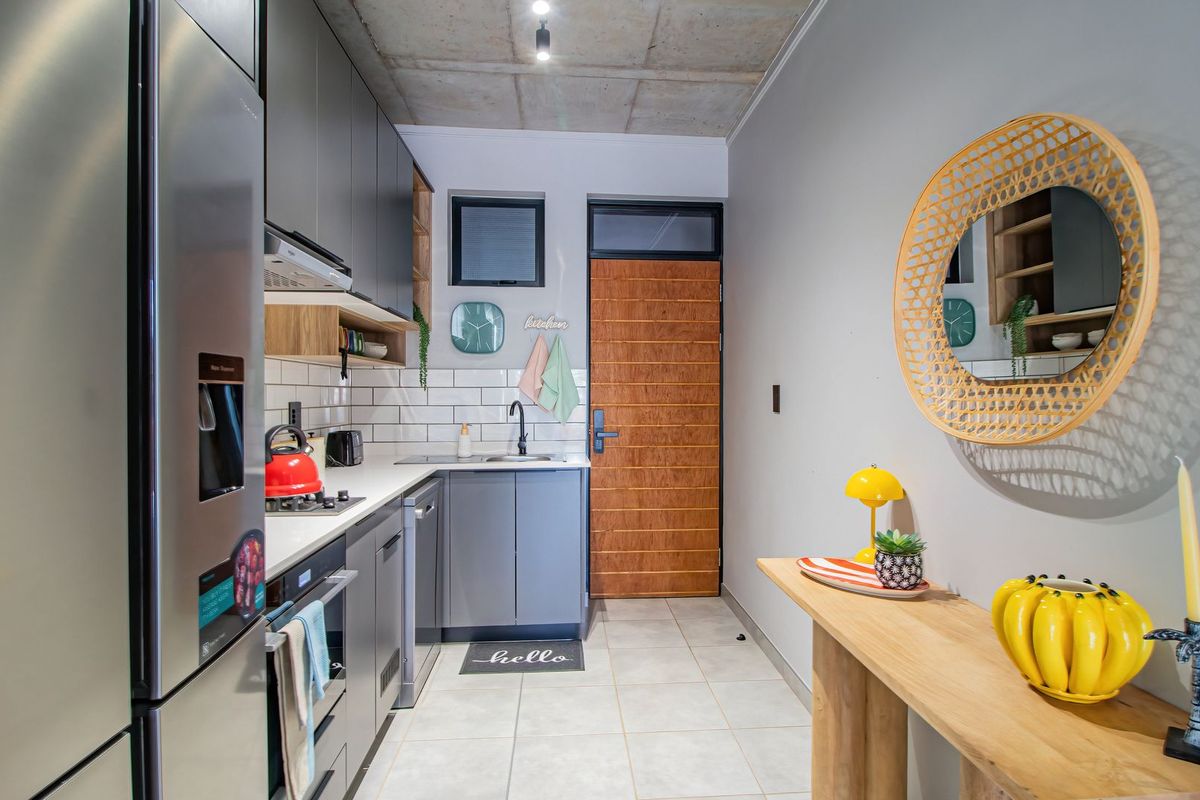 Modern kitchen featuring sleek grey cabinetry, subway tile backsplash, integrated oven, and a distinctive exposed concrete ceiling.