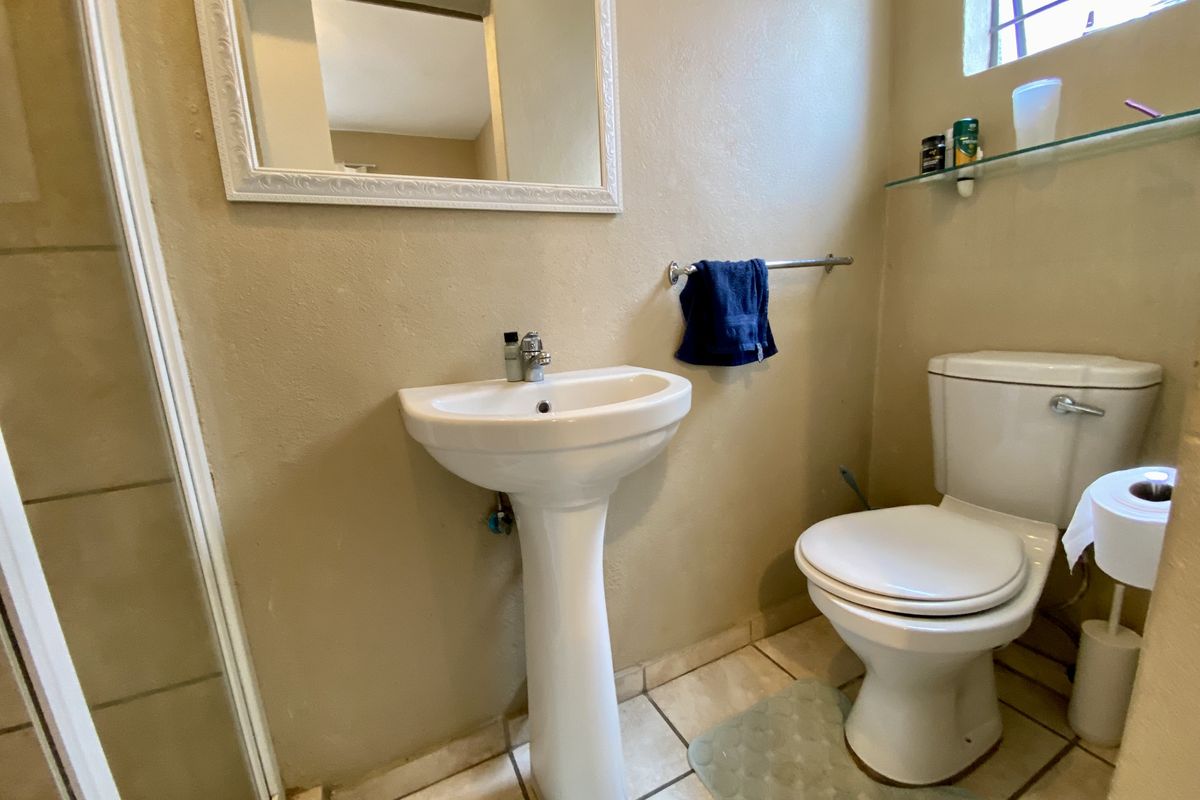 A functional bathroom featuring a pedestal basin, a standard toilet, and a shower enclosure with tiled flooring.