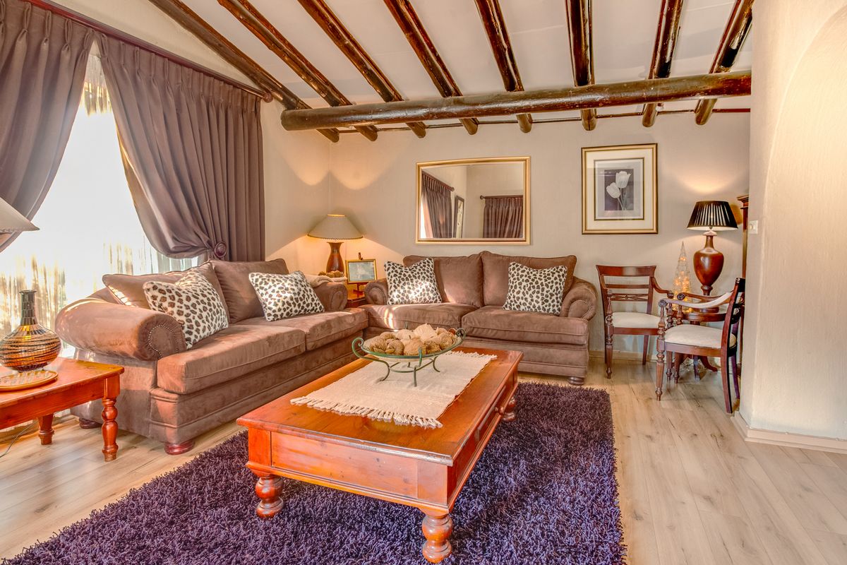 A cozy living room featuring exposed timber ceiling beams and light-toned laminate flooring, creating a warm and inviting atmosphere.