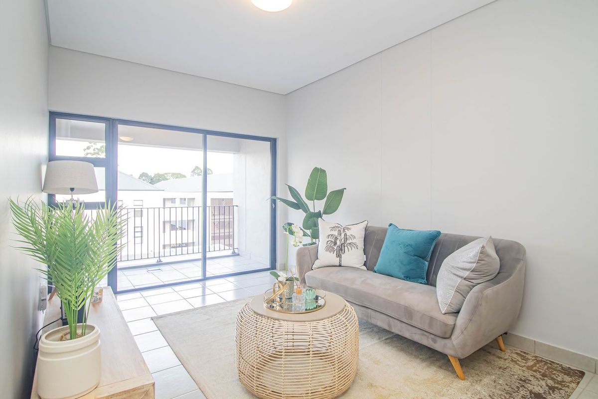 A bright living room featuring tiled flooring and large sliding glass doors that open onto a private balcony.
