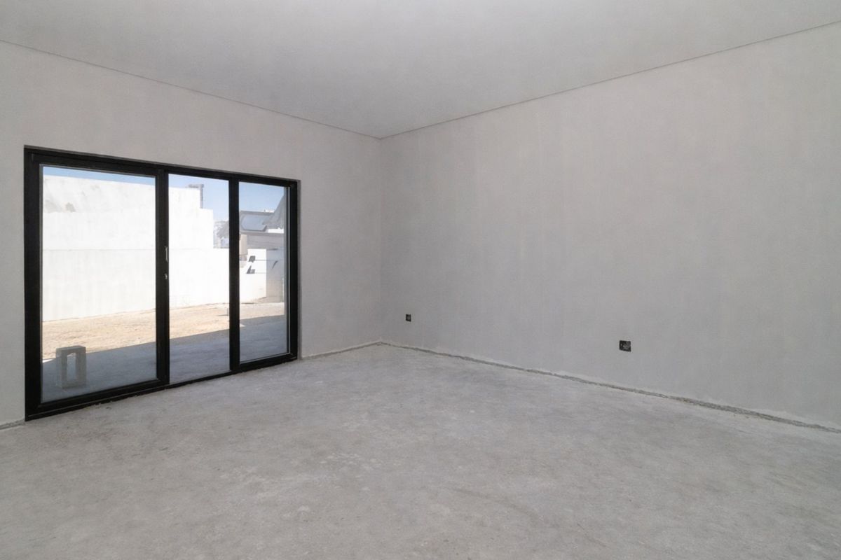 An empty, unfinished room featuring large black-framed sliding glass doors that provide access to the exterior area.