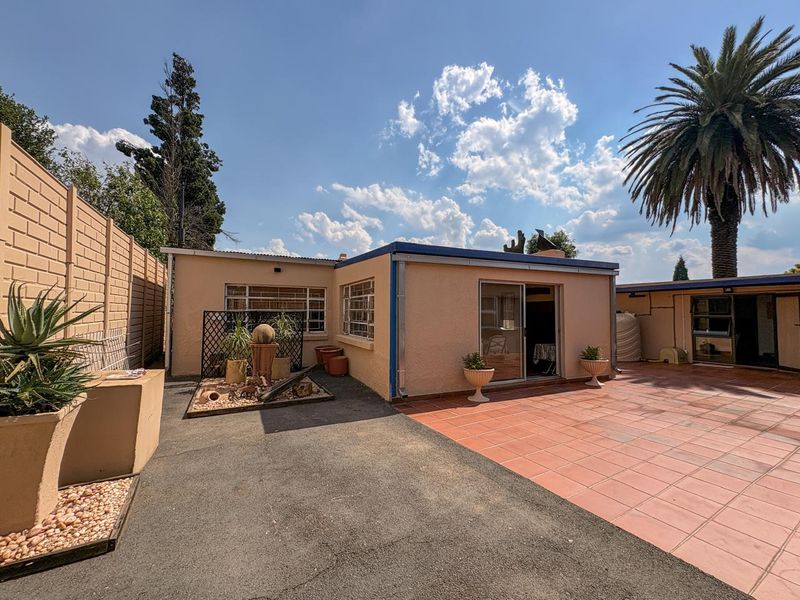 Rear exterior view of the property featuring a paved patio area, low-maintenance garden bed, and sliding door access to the main living space.