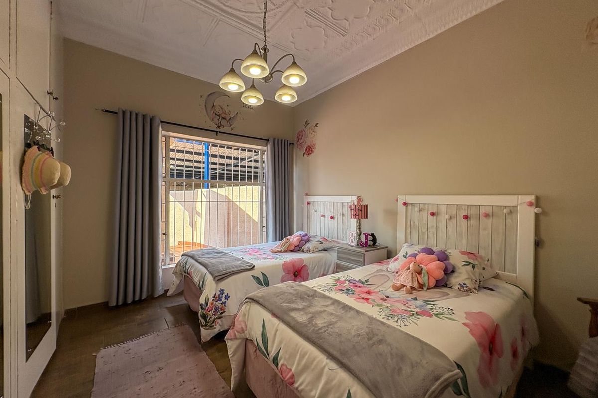 A bedroom featuring decorative pressed metal ceilings, built-in cupboards, and security bars on the window.