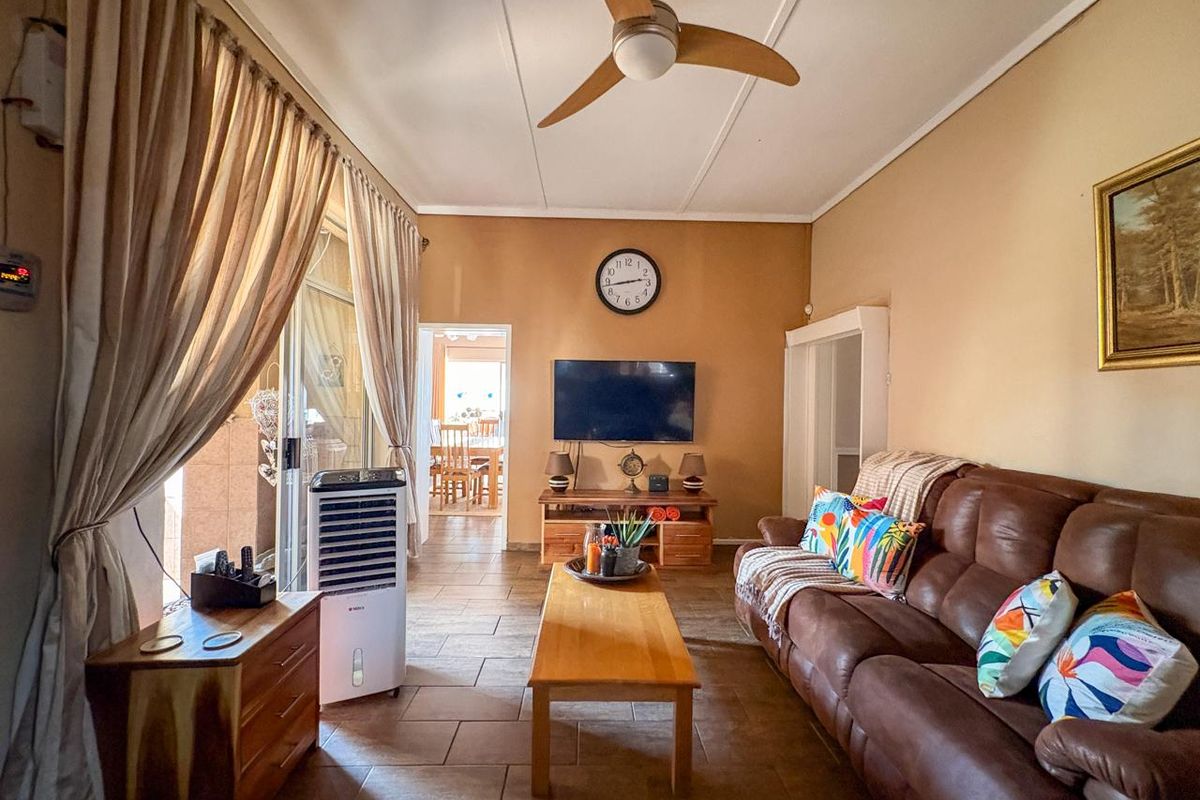 A comfortable living room featuring tiled flooring, a ceiling fan, and sliding glass doors providing access to the outdoor area.