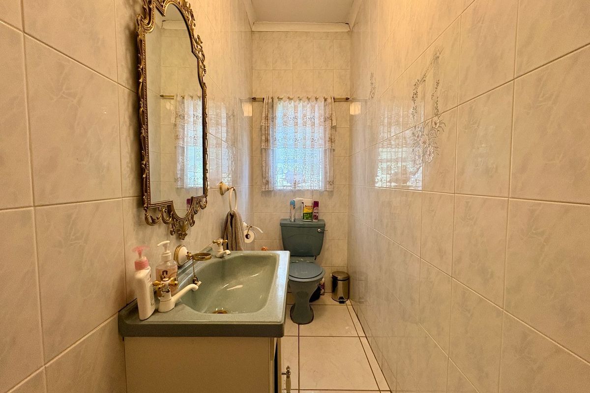 A compact bathroom featuring dated blue sanitary ware, full-height wall tiling, and a vanity basin.