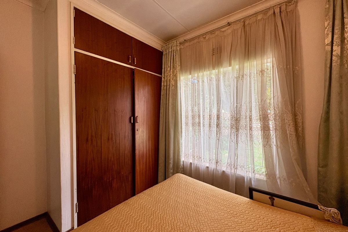 A bedroom featuring built-in wooden cabinetry and a window with natural light, providing a functional and classic living space.