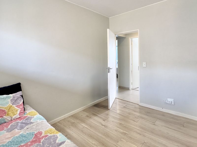 A bright bedroom featuring light-toned laminate flooring and neutral wall finishes, providing a clean and versatile space.