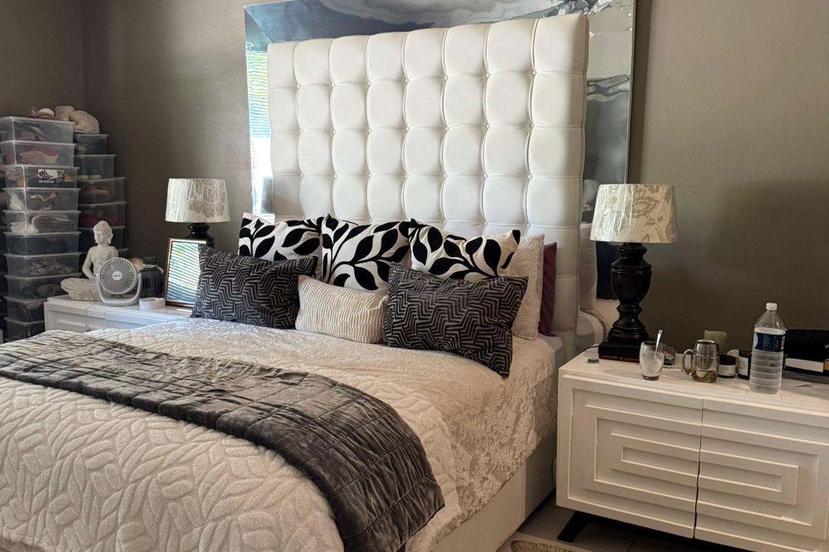 A bedroom featuring a large tufted headboard, tiled flooring, and decorative ceiling cornicing.
