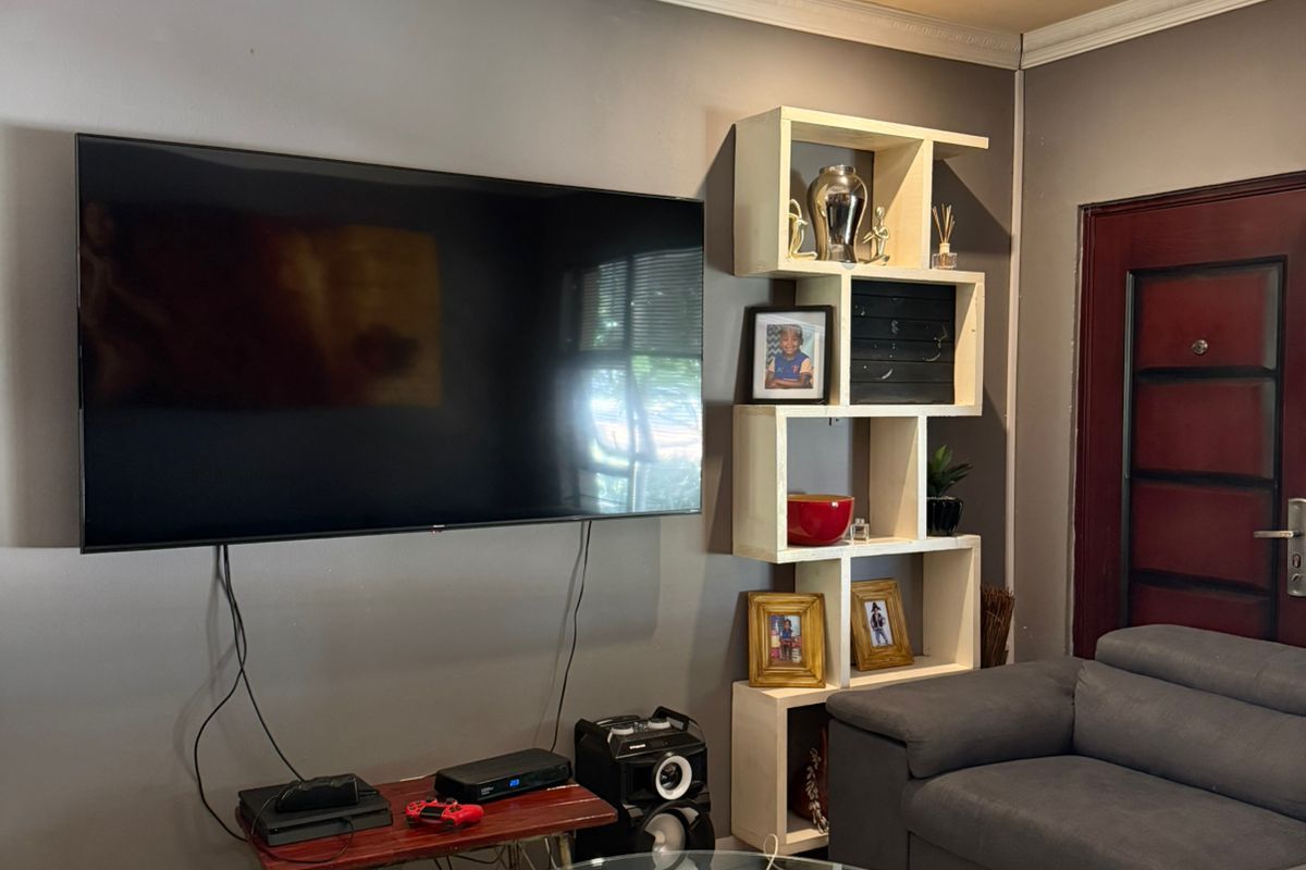 A living room featuring decorative ceiling molding, tiled flooring, and a wall-mounted television setup.