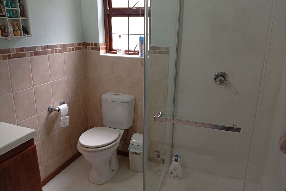 A functional bathroom featuring a glass-enclosed shower, a standard toilet, and tiled wall accents with a neutral color palette.