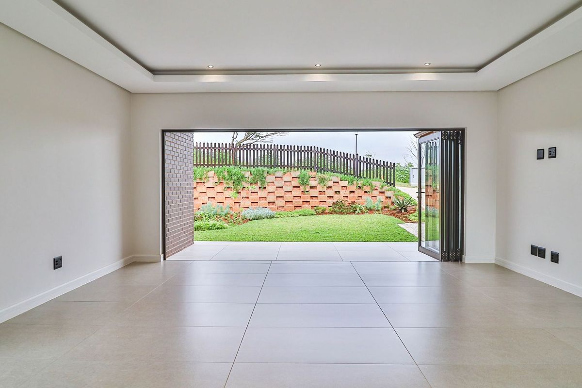Spacious living area featuring large bi-fold doors that open onto a landscaped rear garden with a tiered brick retaining wall.