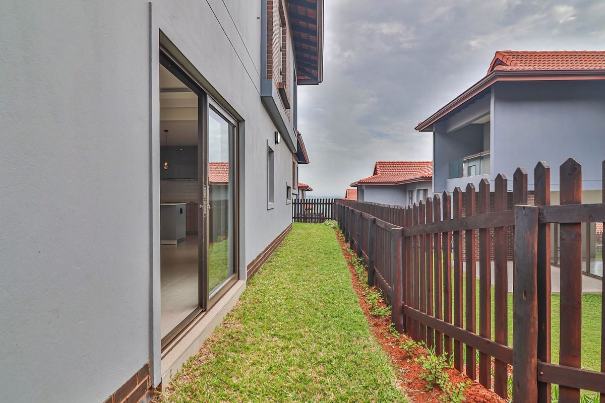 A side garden pathway featuring a manicured lawn, a timber picket fence, and sliding glass door access to the interior living space.