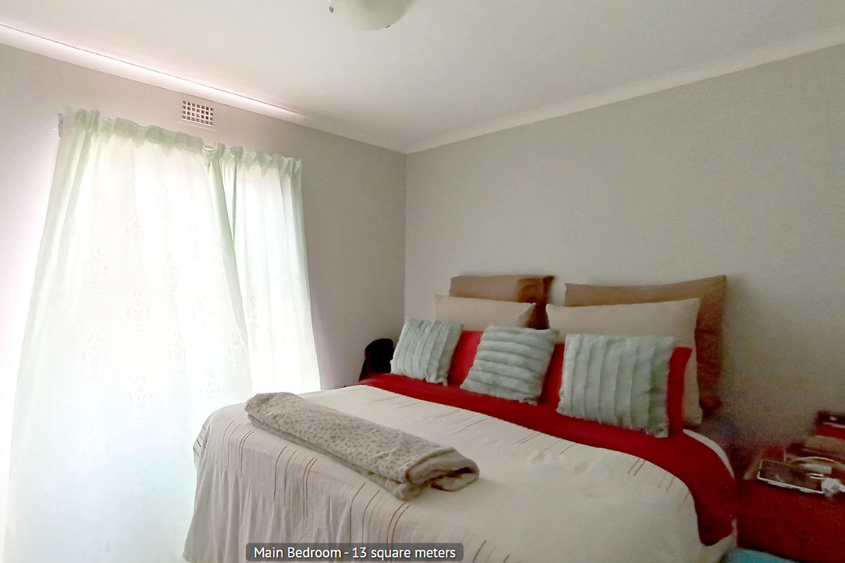 A bedroom featuring neutral walls, a ceiling-mounted light fixture, and a window with curtain tracks.