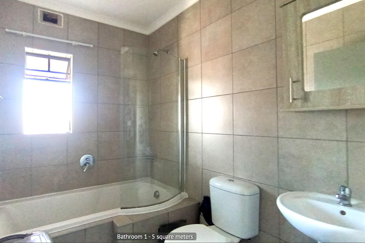 A functional bathroom featuring a bathtub with a glass shower screen, a wall-mounted vanity mirror cabinet, and a standard toilet.