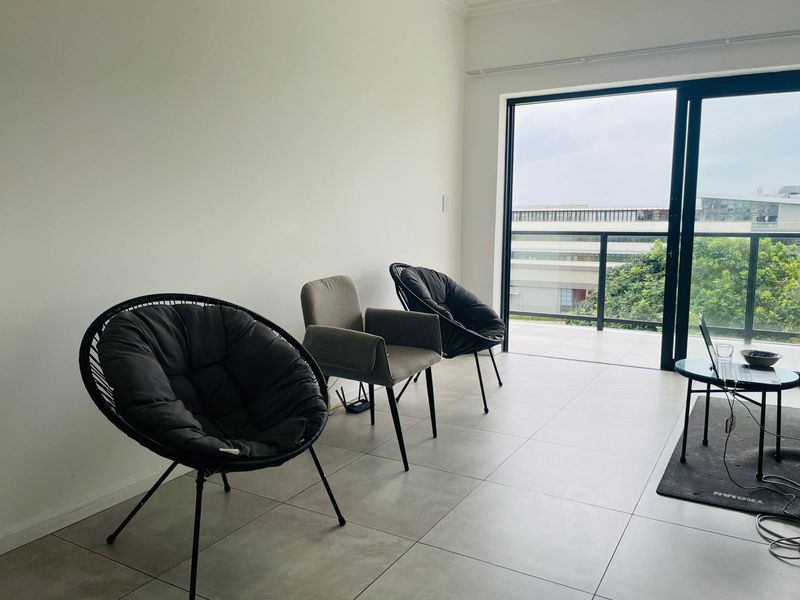 A bright living area featuring large sliding glass doors that open onto a private balcony, providing natural light and outdoor access.