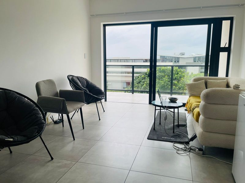 A bright living room featuring large sliding glass doors that open onto a private balcony, providing natural light and views of the surrounding area.