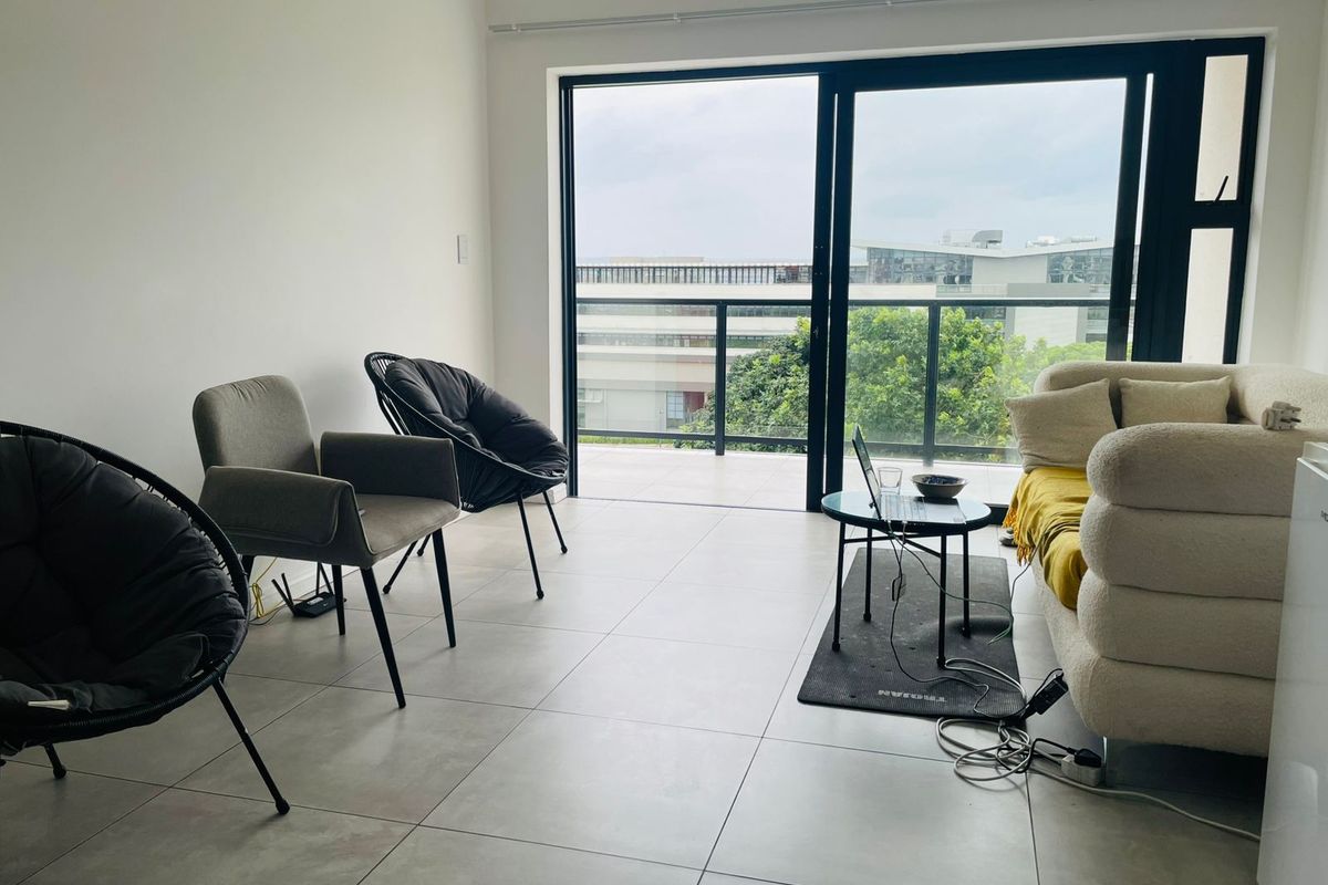 A bright living room featuring large sliding glass doors that open onto a private balcony, providing natural light and views of the surrounding area.