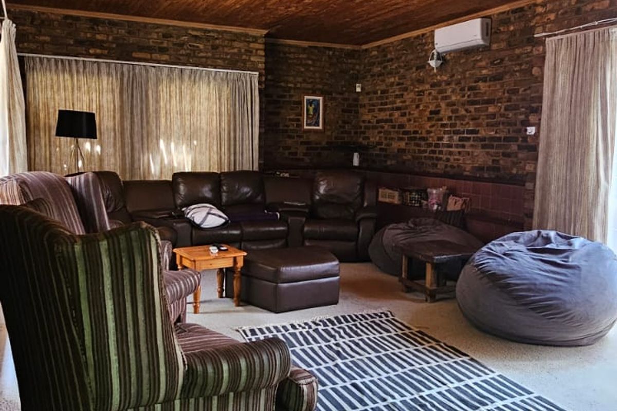 Spacious living room featuring exposed brick walls, a timber-clad ceiling, and a wall-mounted air conditioning unit.