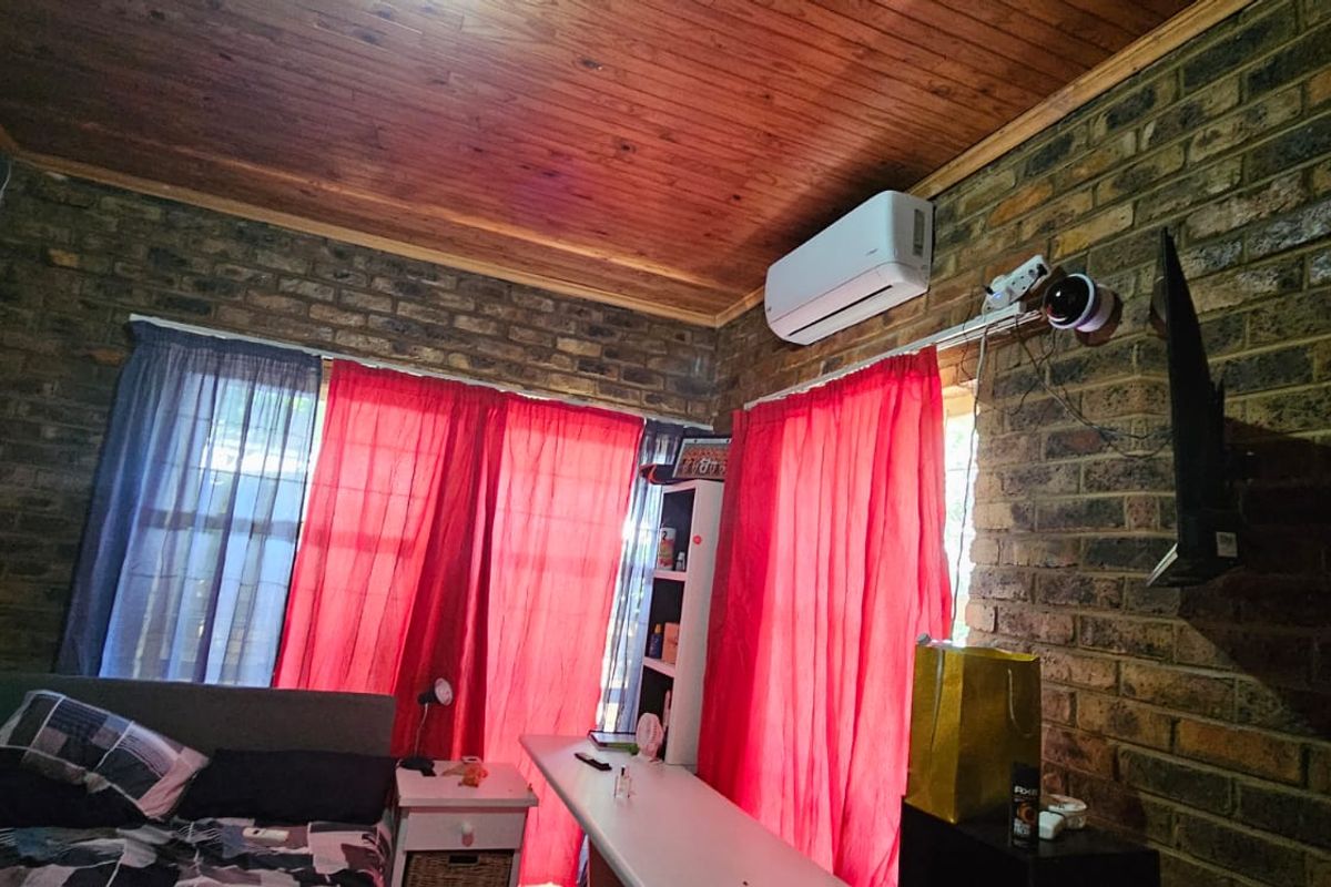 Bedroom featuring exposed face-brick walls, a timber-clad ceiling, and a wall-mounted air conditioning unit.