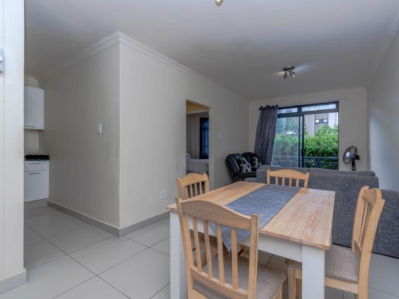 Open plan living and dining area featuring tiled flooring, neutral walls, and sliding glass doors leading to a balcony.