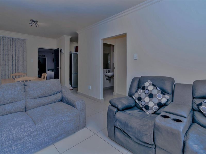 Open plan living area featuring tiled flooring, neutral walls, and direct access to an adjacent bathroom and dining space.
