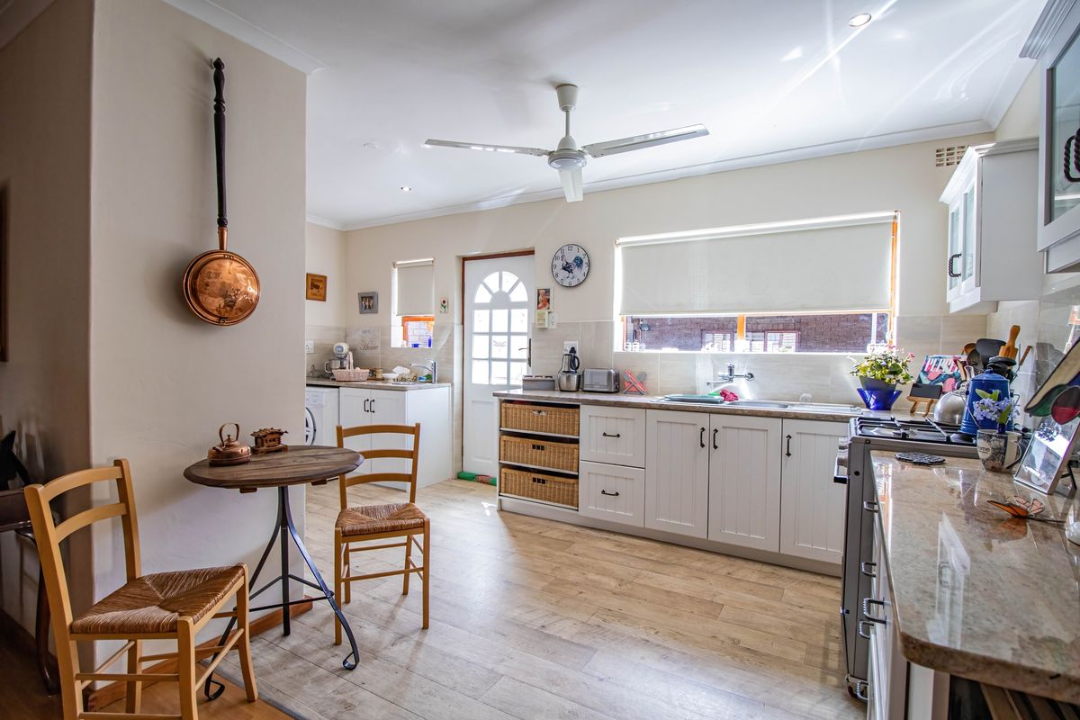 A well-maintained kitchen featuring white cabinetry, granite countertops, a tiled backsplash, and integrated gas stove, with ample natural light and wood-look flooring.