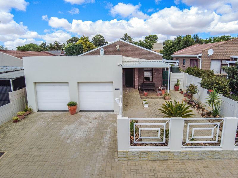 Front view of the property featuring a paved driveway, double garage, and a gated entrance with a covered patio area.