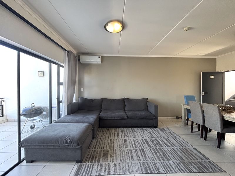Open-plan living and dining area featuring tiled flooring, a split-system air conditioner, and large sliding glass doors leading to an outdoor patio space.