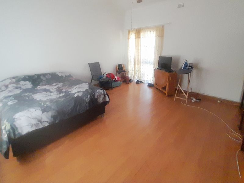 A spacious bedroom featuring laminate flooring and a ceiling fan, offering a blank canvas for potential interior design updates.