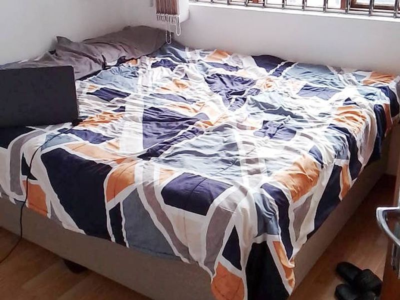 A bedroom featuring laminate flooring and a window fitted with a security gate.