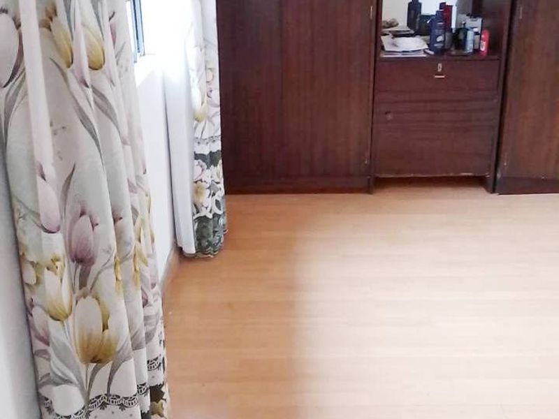 A bedroom featuring laminate flooring and a large, dark wood built-in wardrobe with an integrated vanity mirror.