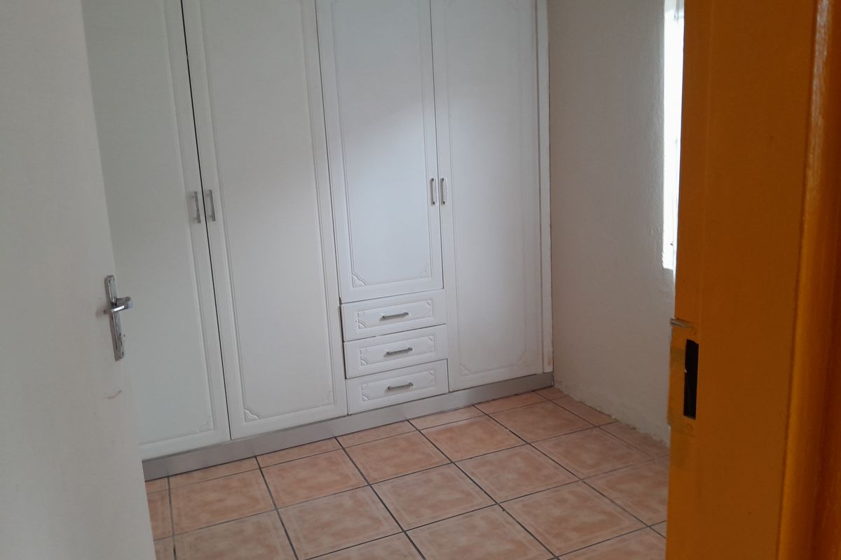 A bedroom featuring built-in white cabinetry with integrated drawers and tiled flooring, viewed from the doorway.