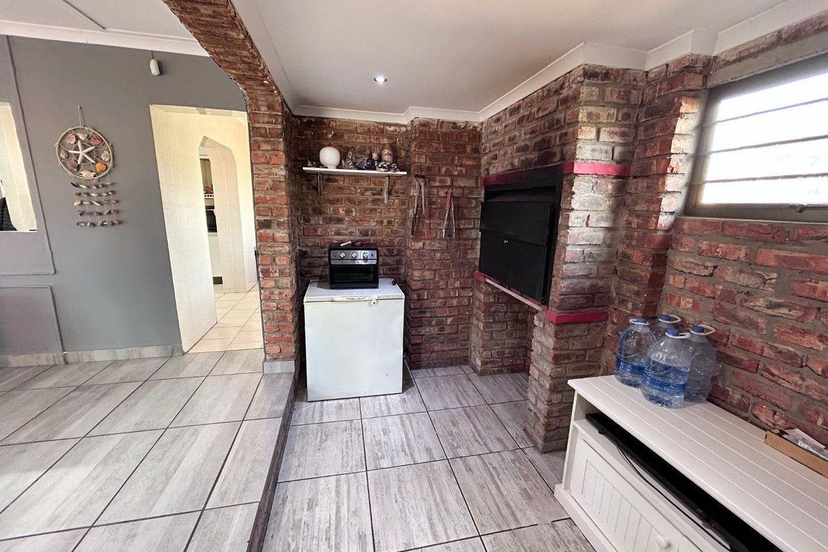 An indoor entertainment area featuring a built-in brick fireplace, tiled flooring, and an arched brick entryway leading to adjacent living spaces.