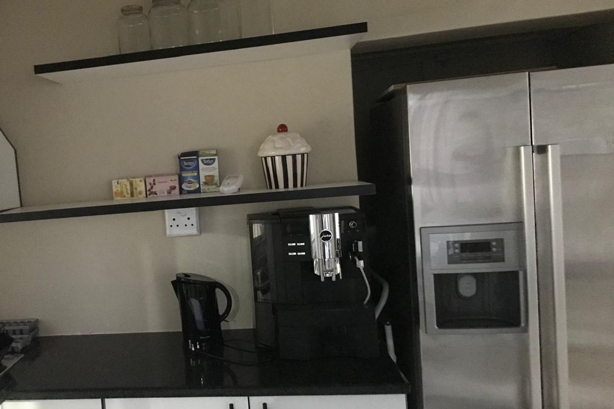 A kitchen area featuring dark stone countertops, white cabinetry, open shelving, and a large stainless steel side-by-side refrigerator.