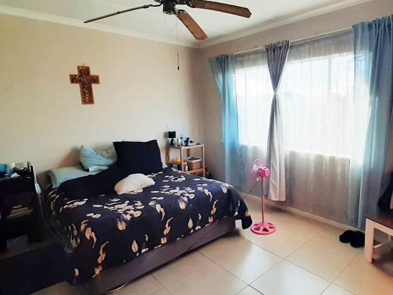 A standard bedroom featuring tiled flooring and a ceiling fan, providing a functional space with natural light from the window.