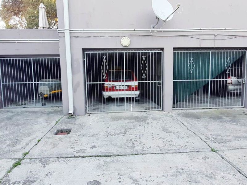 A multi-bay garage area featuring metal security gates and a concrete driveway, showing signs of weathering and wear.