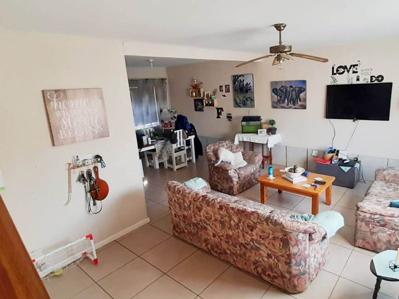 Open plan living area featuring tiled flooring, a ceiling fan, and an adjacent staircase leading to the upper level.