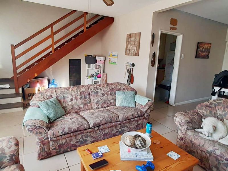 Open plan living area featuring tiled flooring and a wooden staircase leading to the upper level.