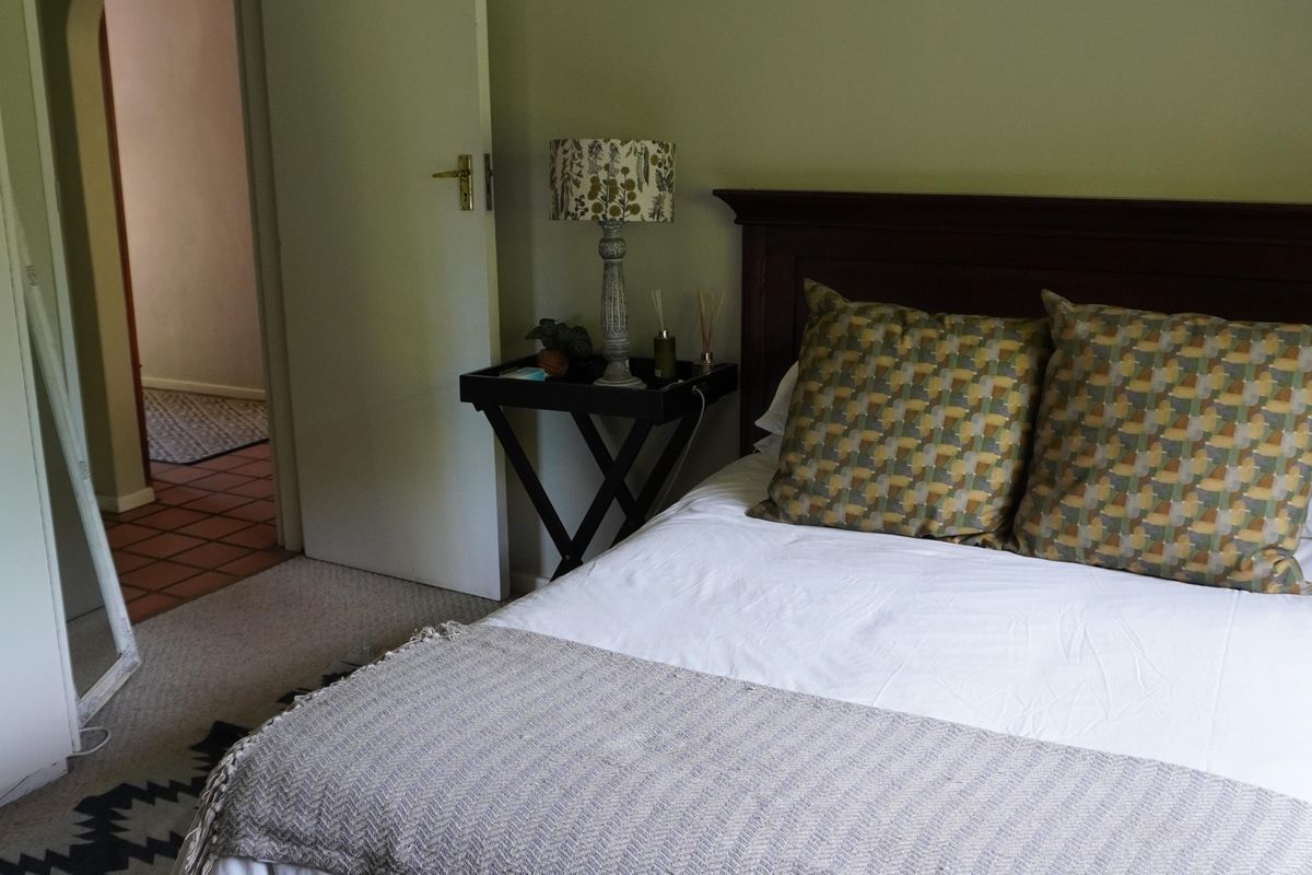 A bedroom featuring neutral wall tones, carpeted flooring, and an arched doorway leading to an adjacent space.