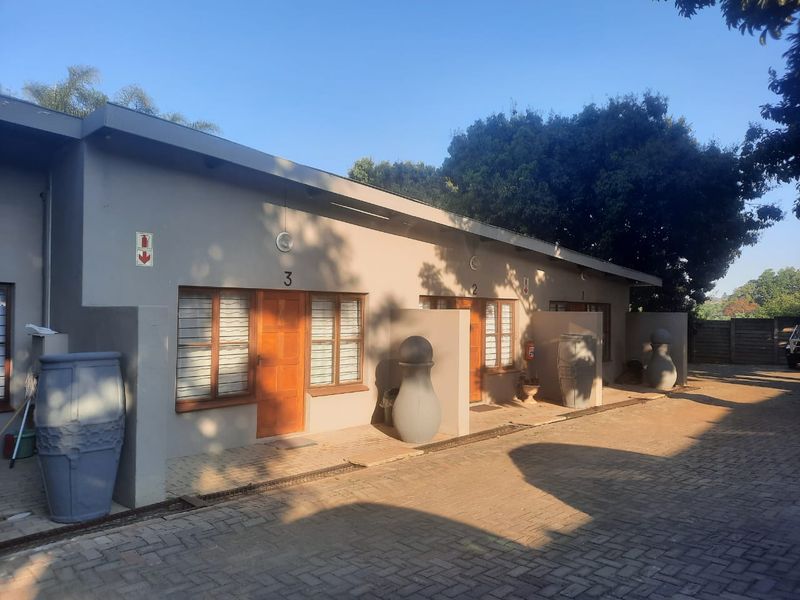 Exterior view of an apartment complex featuring a paved driveway and individual unit entrances with numbered doors.