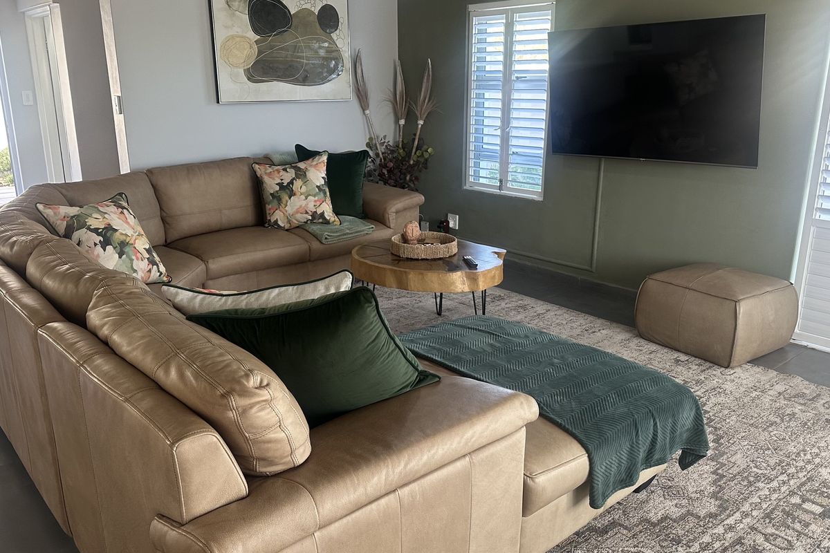 A comfortable living room featuring tiled flooring and plantation shutters, providing a bright and well-maintained space for relaxation.