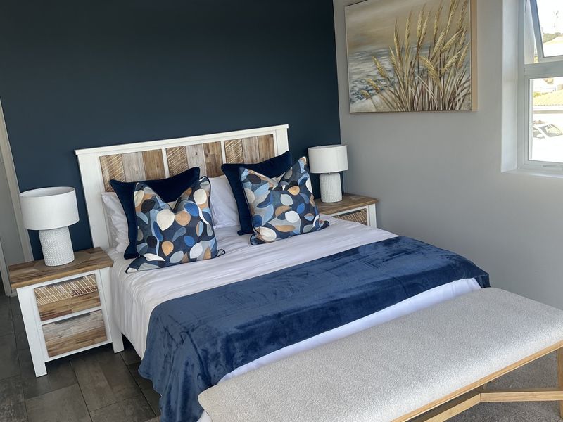 A well-maintained bedroom featuring a mix of tiled and carpeted flooring, a dark blue accent wall, and natural light from an aluminium-framed window.