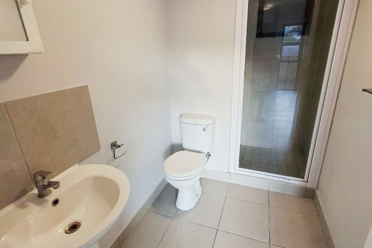 A functional bathroom featuring a pedestal basin, toilet, and a separate shower enclosure with tiled flooring throughout.